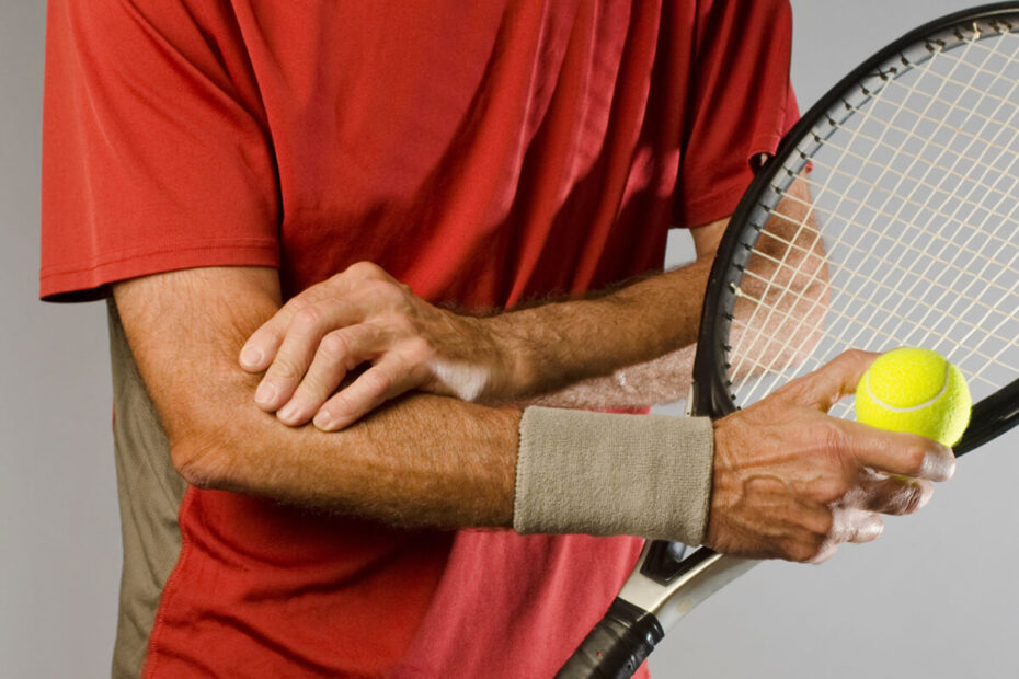 tennis player holding racket and tennis ball rubbing elbow from pain